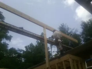 Carpenter setting a ridge beam over a new addition frame — Ice Dam Removal by Roofing Brothers in Poolville