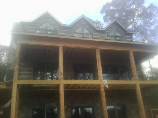 Dormers and porch framing on a large log home under construction — Roof Coating work by our crew in Poolville