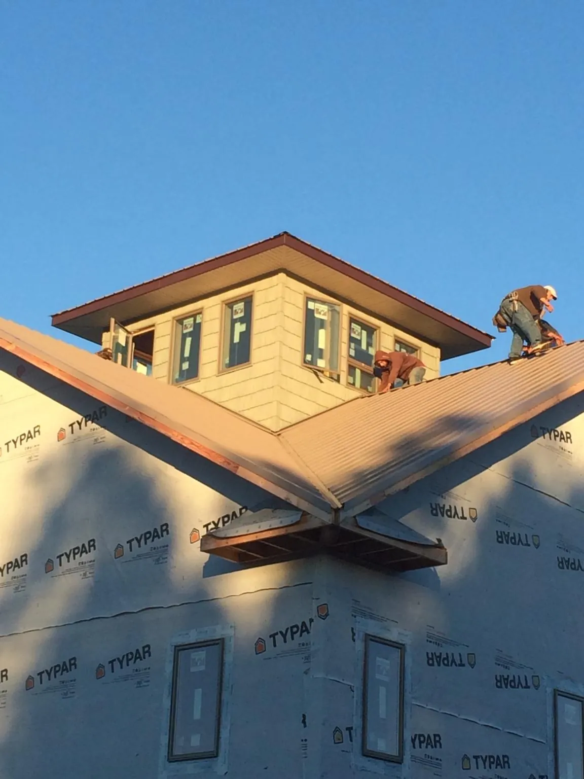 Roofers working around a rooftop cupola on a new metal roof at sunset — Roof Waterproofing in Poolville by Roofing Brothers